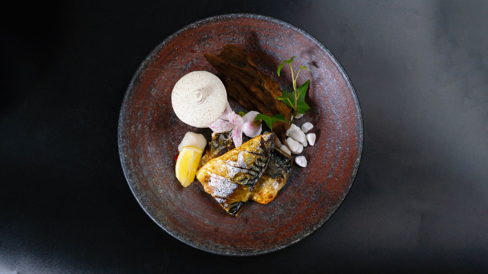 Pescado de temporada emplatado sobre fondo oscuro